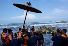 Dozens of Yogyakarta Palace royal servants and the search and rescue staff carry offerings to be thrown into the sea on April 27, 2017. The offerings include batik, which signifies the coronation anniversary of Hamengkubuwono X. JP/Tarko Sudiarno