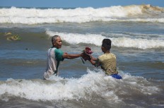 Men collect some of the offerings at Parang Kusumo Beach, Yogyakarta, on May 19, 2015.  JP/Tarko Sudiarno