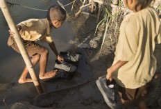 Tidy up: A child laces his shoes after crossing a 65-meter-wide river. JP/ Tarko Sudiarno