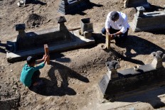 A man and a child pray beside the grave of one of their relatives during the ceremony. JP/Stefanus Ajie