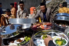 Some villagers share food kept inside tenong (containers made of aluminum or bamboo), which they brought from home during the ceremony. JP/Stefanus Ajie