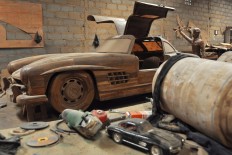 A teakwood replica of a Mercedes-Benz 300 SL gull-wing is in the background while the model of the car is in the foreground. JP/Magnus Hendratmo
