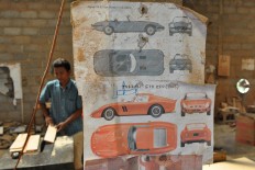 Diagrams of a Jaguar XK E-type and a Ferrari GTO 250 are tacked to a pillar to be used as guidelines. It takes one month to make one teakwood replica. JP/Magnus Hendratmo