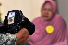 Rusidah checks the result of her photoshoot on her camera's LCD. JP/Magnus Hendratmo