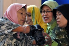 Rusidah shows pictures to her clients that can be printed postcard size and sell for Rp 20,000 each. JP/Magnus Hendratmo