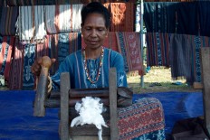 Processing cotton using a simple manual wooden machine. JP/Intan Tanjung
