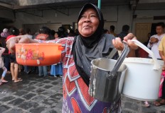 Happy go lucky: A woman smiles after securing three portions of porridge. JP/ Ganug Nugroho Adi