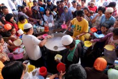 First-come, first-served: Mosque committee members distribute the porridge to hundreds of residents who come from nearby neighborhoods and outside the kampung. JP/ Ganug Nugroho Adi