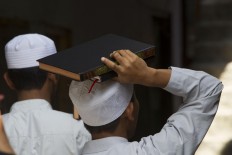 A santri carries a Quran on his head on his way to the mosque to study it while waiting to break the fast. JP/Sigit Pamungkas