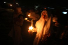 A female santri (student) carries an oil lamp to join in the tadarus (mass Quran recital) at Mojosongo, Surakarta, Central Java, on June 11. JP/Maksum Nur Fauzan