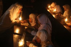 Students at the Baitul Mustofa Islamic boarding school are accompanied by an ustadzah (female Muslim teacher) to recite the Quran outdoors with oil lamps as their lighting at Mojosongo, Surakarta, Central Java, on June 11. The event is an annual activity to commemorate Nuzulul Quran (the night when the Quran was sent down to Prophet Muhammad). JP/Maksum Nur Fauzan