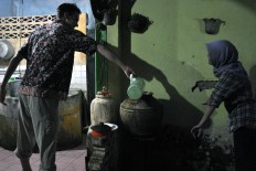 Martin, a mualaf (Islamic convert) from the United States, fills a water barrel for wudu (ritual purification). JP/Magnus Hendratmo