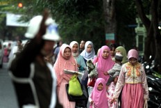 Muslim women walk to Sudirman mosque as an officer guides the way in Denpasar, Bali, to observe the Idul Fitri mass prayer on Sunday, June 25, 2017. JP/ Zul Trio Anggono