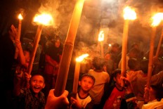 Children carry bamboo torches aloft during takbiran, chanting “Allah is great”, on the eve of Idul Fitri at the Kasunanan palace complex in Surakarta, Central Java, on Saturday, June 24, 2017. JP/Ganug Nugroho Adi