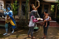 Sharing is caring: Dwi Dharmawanti (left) hands a traditional ketupat to her Hindu neighbor, Diana Kristiani (right) during the ketupat festivity in Pesanggrahan village, Banyuwangi. JP/Aman Rochman