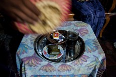 A glass of coffee, snacks and cigarettes are served on a table. The coffee is usually mixed with sugar and shrimp paste as a prank to symbolize the potential hardships of married life. JP/Anggara Mahendra