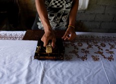 A craftsman stamps the Alas Purwo motif on white fabric at the Batik Satrio cottage industry in Senepo Rejo village, Banyuwangi, East Java, on Saturday, May 20. The workshop produces 13,000 beach sarongs a month. JP/Aman Rochman