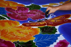 A close-up of the dyeing process shows how each color of a gradient scheme is applied painstakingly by hand. For all the craftsmanship and time invested in creating a sarong, each one is priced from Rp 40,000 to Rp 60,000. JP/Aman Rochman