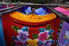 Ahmad, 18, hangs beach sarongs in the final drying step before they are ready to be packaged and sold. JP/Aman Rochman