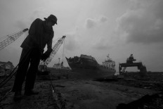 A worker cutting metal on a dock in Kamal, Madura Island, East Java, on Monday, Jan. 23, 2017. The sheet metal is sold to a smelter. Each worker earns Rp 100,000 per day. JP/Sigit Pamungkas