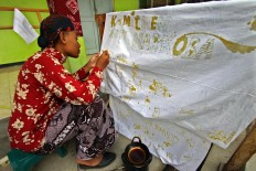 A new student signs an integrity pact using a canting (a pen-like tool used in making batik). The pact said they would not become involved in violent acts and drugs. JP/Aditya Sagita