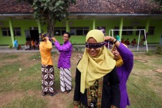 Two new students help classmates put on blindfolds during the masangin competition in which participants run between two trees. JP/Aditya Sagita