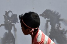 A boy watches the shadow puppet show featuring the Norontoko story. JP/ Magnus Hendratmo
