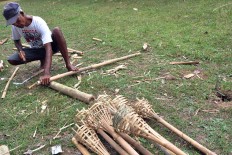 A man makes bamboo torches for the Eucharistic mass. JP/ Magnus Hendratmo