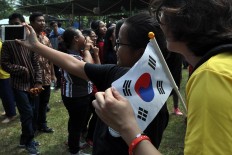 A Korean participant in the 2017 Asian Youth Day, holding her country’s flag, has her photo taken during the Srawung Asih performance. JP/ Magnus Hendratmo