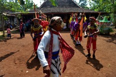 A man wearing a mask dances in front of a Bejiharjo village leader to collect cone offerings. JP/Stefanus Ajie