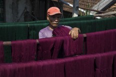 Processing: A man puts threads that have been colorized under the sun so that they can last longer. JP/ Sigit Pamungkas