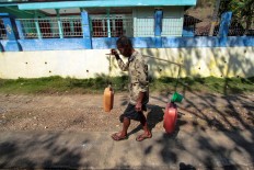 A villager carries home two jerrycans filled with water. JP/Aditya Sagita