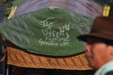 A man stands before an ox-drawn cart participating in the festival. JP/Maksum Nur Fauzan