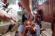 A girl receives holy water from a priest during the Tumpek Pengatag ceremony and drinks it. JP/Anggara Mahendra