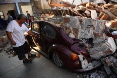 A man tries to open his Beetle's car, crashed by debris from his house which was damaged by a powerful earthquake that struck Mexico's Pacific coast late on September 7, in Juchitan de Zaragoza, Mexico, on September 9, 2017.
Police, soldiers and emergency workers raced to rescue survivors from the ruins of Mexico's most powerful earthquake in a century, which killed at least 61 people, as storm Katia menaced the country's eastern coast Saturday with heavy rains. AFP/ Ronaldo Schemidt