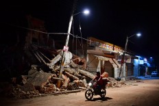A man rides his motorbike in Juchitan de 
Zaragoza, state of Oaxaca on September 9, 2017, the day after an 8.2 magnitude earthquake hit Mexico's Pacific coast, Rescuers pulled bodies from the rubble and grieving families carried coffins through the streets after Mexico's 
biggest earthquake in a century killed 65 
people, while elsewhere two died in mudslides unleashed by storm Katia. AFP/ Ronaldo Schemidt