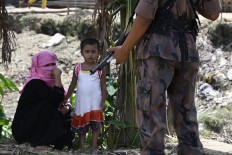 A Bangladesh border guard stands guard at the Jalpatoli refugee camp for Rohingya Muslims in the no-man's land area between Myanmar and Bangladesh, near Gumdhum village in Ukhia on September 16, 2017. According to the UN nearly 400,000 Rohingya have arrived in Bangladesh since August 25 after fleeing a military crackdown launched by Myanmar's military in response to attacks by Rohingya rebels. AFP/ Dominique Faget 