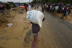 A Rohingya Muslim refugee carries a rice bag along a road near Balukhali refugee camp near the Bangladesh town of Gumdhum on September 17, 2017.
Heavy monsoon rain heaped new misery September 17 on hundreds of thousands of Muslim Rohinyga stuck in makeshift camps in Bangladesh after fleeing violence in Myanmar, as authorities started a drive to force them to a new site. The United Nations says 409,000 Rohingyas have now overwhelmed Cox's Bazar since August 25 when the military in Buddhist-majority Myanmar launched operations in Rakhine state. AFP/ Dominique Faget 