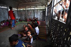 Rohingya Muslim refugee children sit inside a school in Leda refugee camp near the Bangladeshi town of Teknaf on September 18, 2017. Pressure grew on Myanmar September 18 as a rights group urged world leaders to impose sanctions on its military, which is accused of driving out more than 410,000 Rohingya Muslims in an orchestrated "ethnic cleansing" campaign. The exodus of Rohingya refugees from mainly Buddhist Myanmar to neighbouring Bangladesh has sparked a humanitarian emergency. Aid groups are struggling to provide relief to a daily stream of new arrivals, more than half of whom are children. AFP/ Dominique Faget 