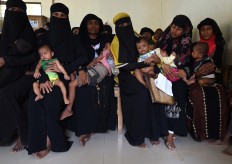Rohingya Muslim refugees wait with their children for a consultation at a clinic run by the International Organisation for Migration (IOM) in Leda refugee camp near the Bangladeshi town of Teknaf on September 18, 2017. Pressure grew on Myanmar September 18 as a rights group urged world leaders to impose sanctions on its military, which is accused of driving out more than 410,000 Rohingya Muslims in an orchestrated "ethnic cleansing" campaign. The exodus of Rohingya refugees from mainly Buddhist Myanmar to neighbouring Bangladesh has sparked a humanitarian emergency. Aid groups are struggling to provide relief to a daily stream of new arrivals, more than half of whom are children. AFP/ Dominique Faget 