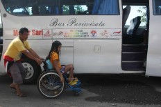 An NPC official pushes wheels an athlete to board the bus as the Indonesian delegation departs on their journey to the top. JP/Maksum Nur Fauzan