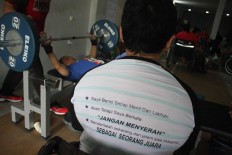 An athlete wears a T-shirt with motivational words printed on it, which begins humorously with, “I hate every minute of training...,” and ends with the statement: “I will suffer now and live the rest of my life as a champion." JP/Maksum Nur Fauzan