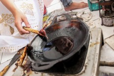 Drawing technique: A batik artisan dips her canting to the hot wax in Sekar Purnama Gallery in South Tangerang, Banten. JP/Ibrahim Irsyad