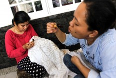 Manual work: Two batik artisans apply wax to the hand-drawn motifs. 
JP/Ibrahim Irsyad