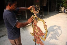 Agung holds a puppet made of used parts to be Sun dried. JP/Maksum Nur Fauzan