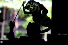 Action: A silhouette of a young puppet master performing a play. JP/ Maksum Nur Fauzan