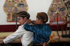 Helping hand: A junior pupper master helps a colleague with his costume. JP/ Maksum Nur Fauzan