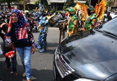 A mother and her son walk in front of carnival participants. JP/Aman Rochman