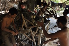 Gold miners work together to pull the pulleys from the bottom of the gold mine, which is 125 meters deep. The miners have a sharing concession with the land owner. JP/ Magnus Hendratmo