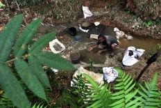 Villagers in Nglenggong use the miner’s plate to check if there are gold particles in the river stream. JP/ Magnus Hendratmo